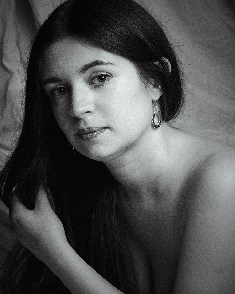 Boudoir photo of a woman looking sensual, bare shoulders with an earring in her ear.