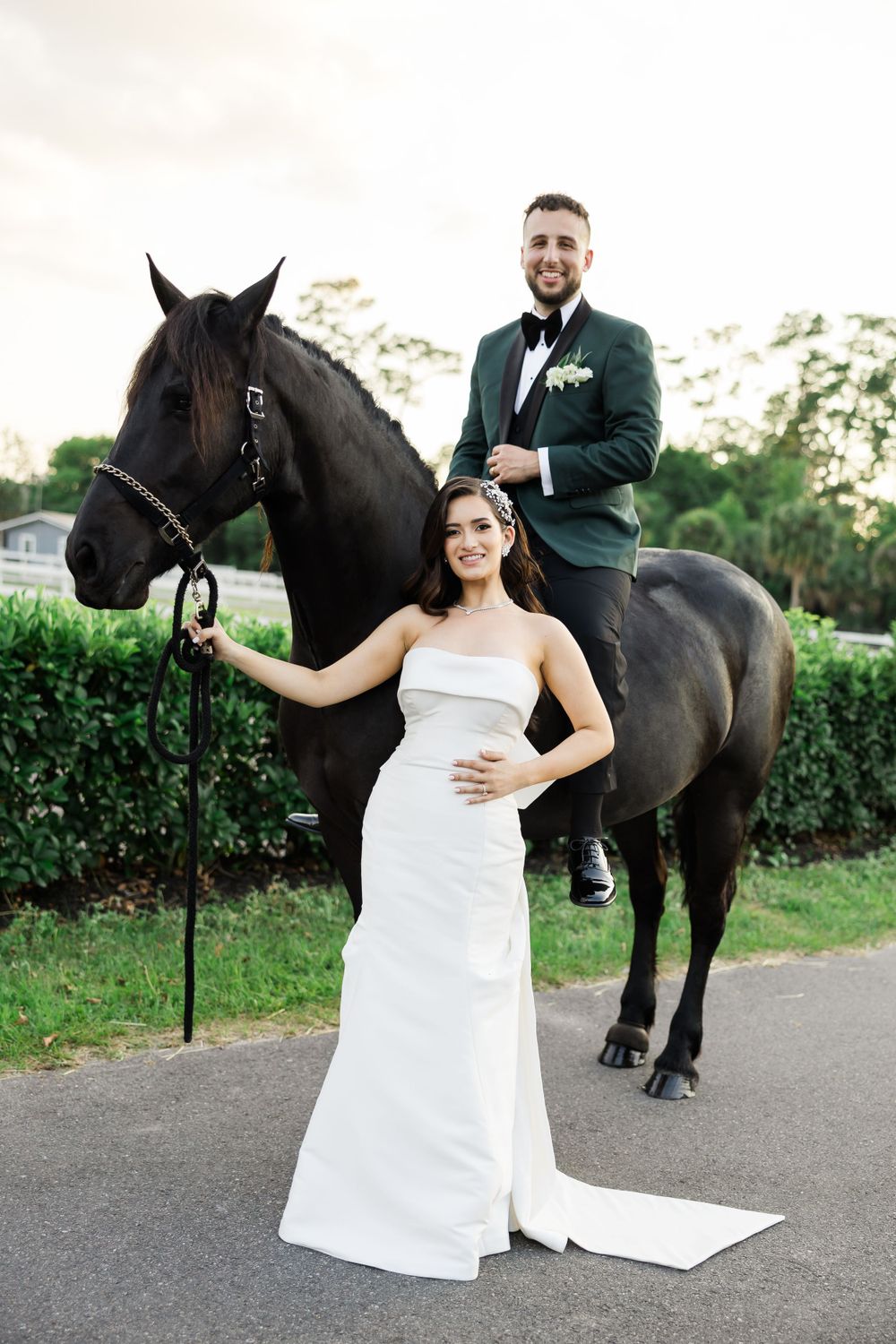 A stately black horse accompanies a couple in wedding attire for outdoor portraits.