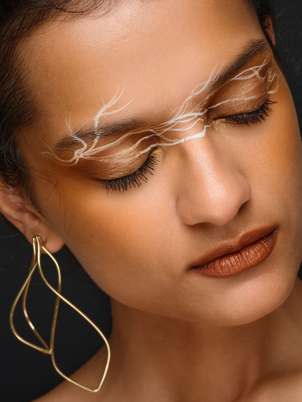 Artistic beauty close-up featuring delicate white eyelash extensions and gold jewelry.