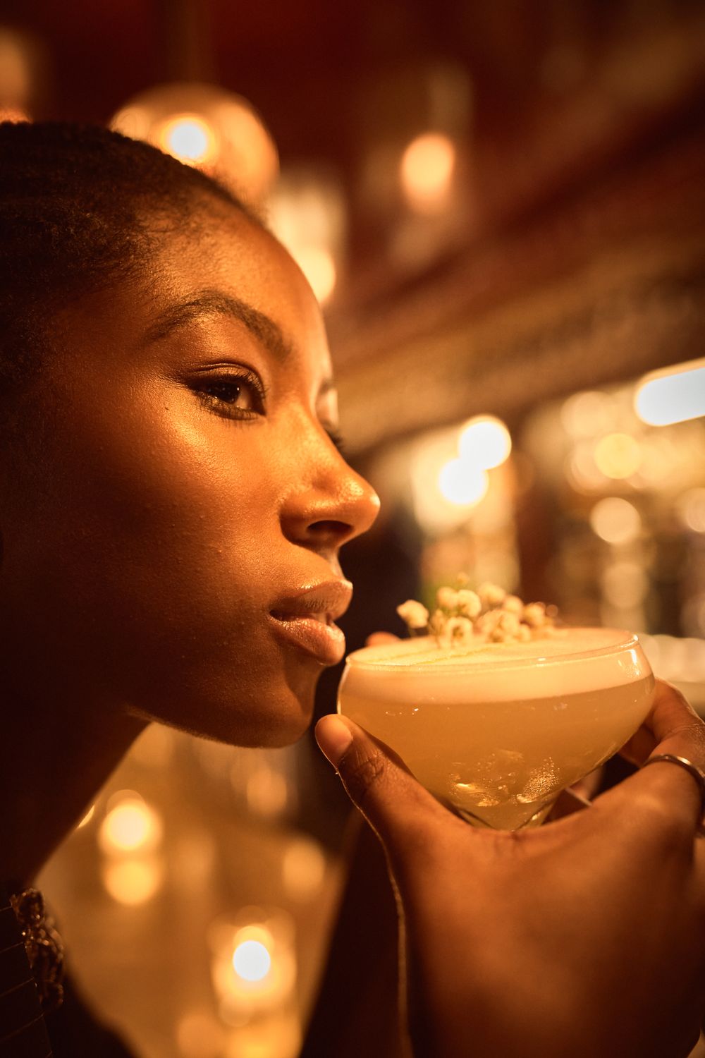 Atmospheric shots of person sipping from cocktail glass in dimly lit bar setting.