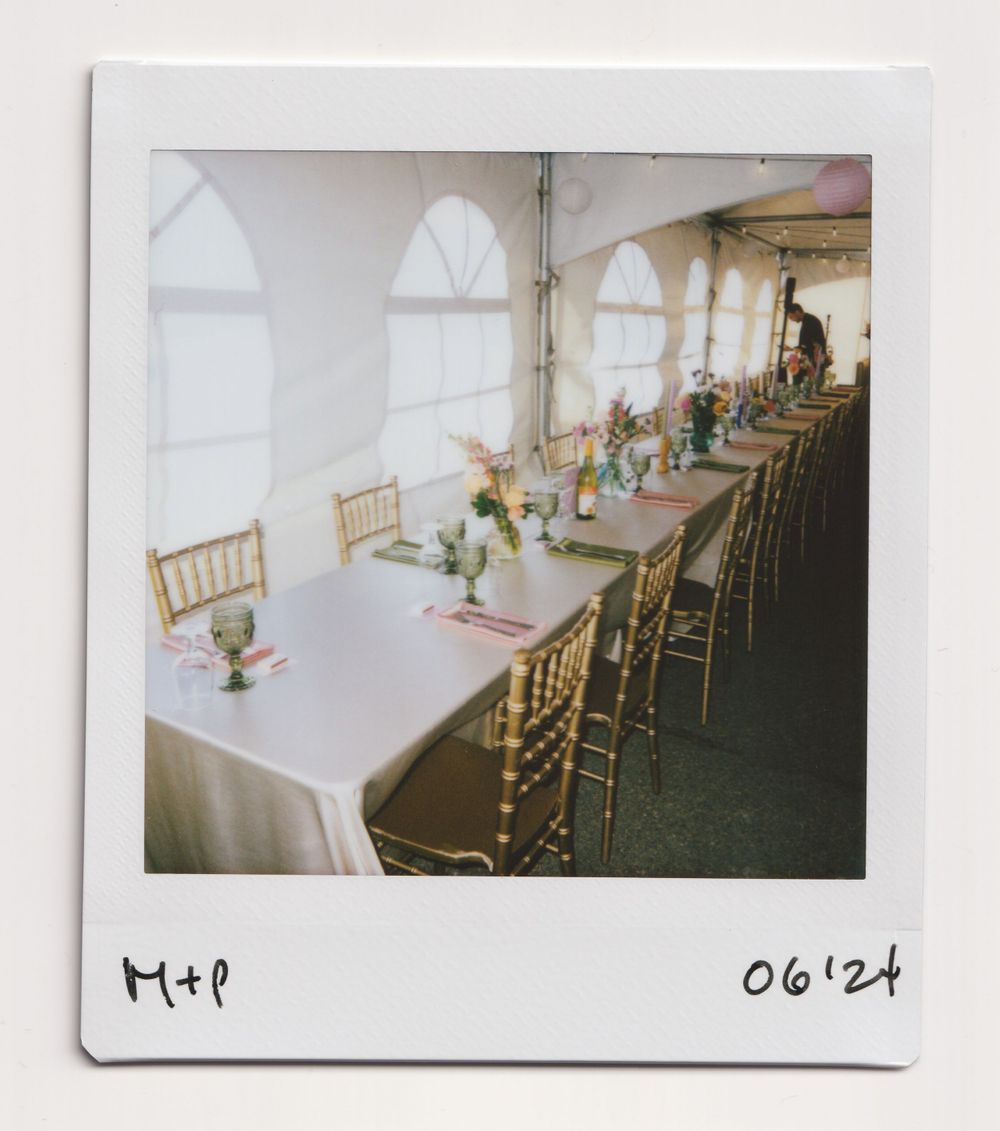 Elegant wedding reception table setup with gold chairs and floral centerpieces in a bright venue.