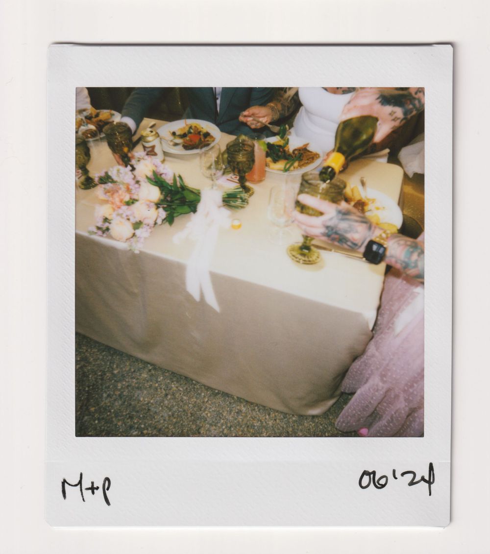 A table set for a wedding reception with food and decorative elements on a white tablecloth.