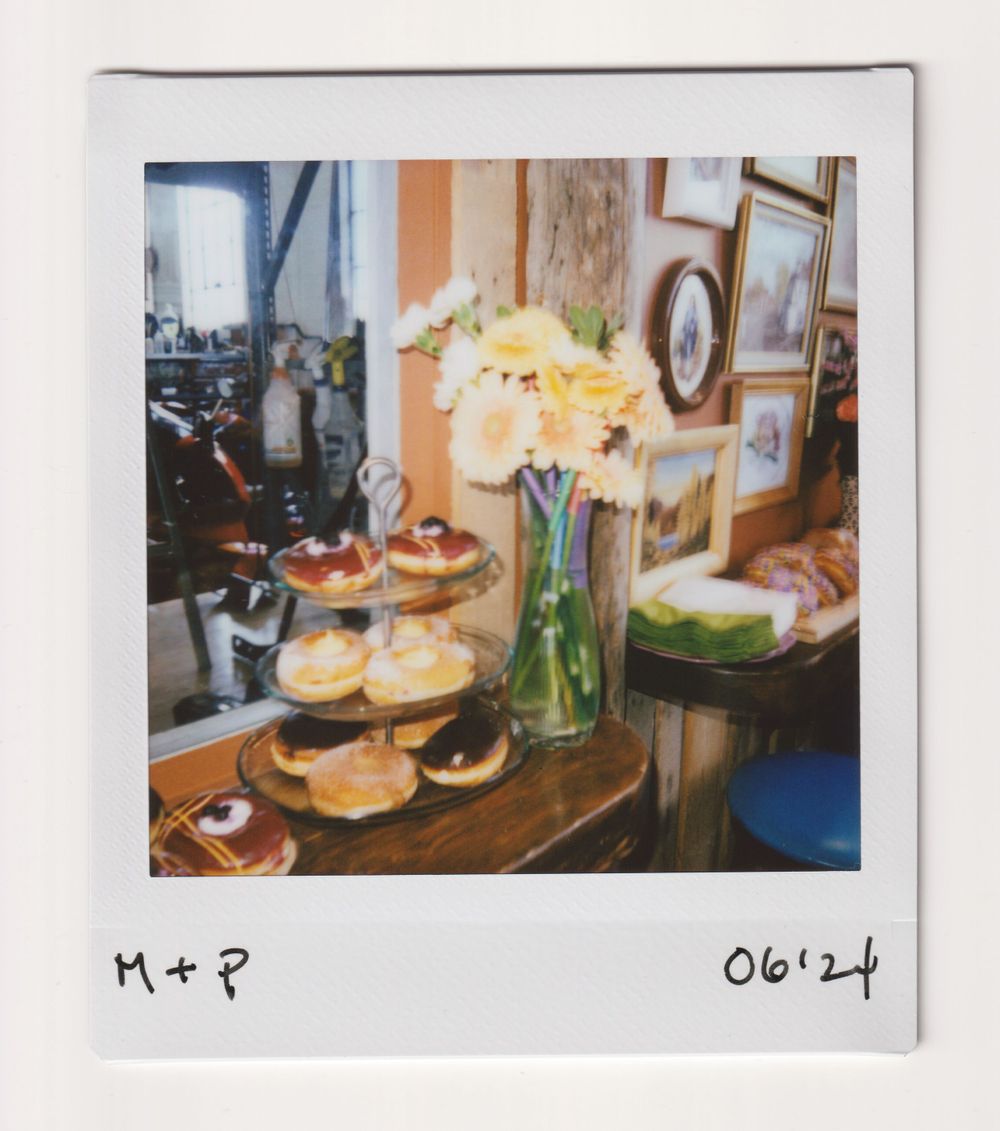 Dessert table with yellow flowers in a vase and various pastries on display.