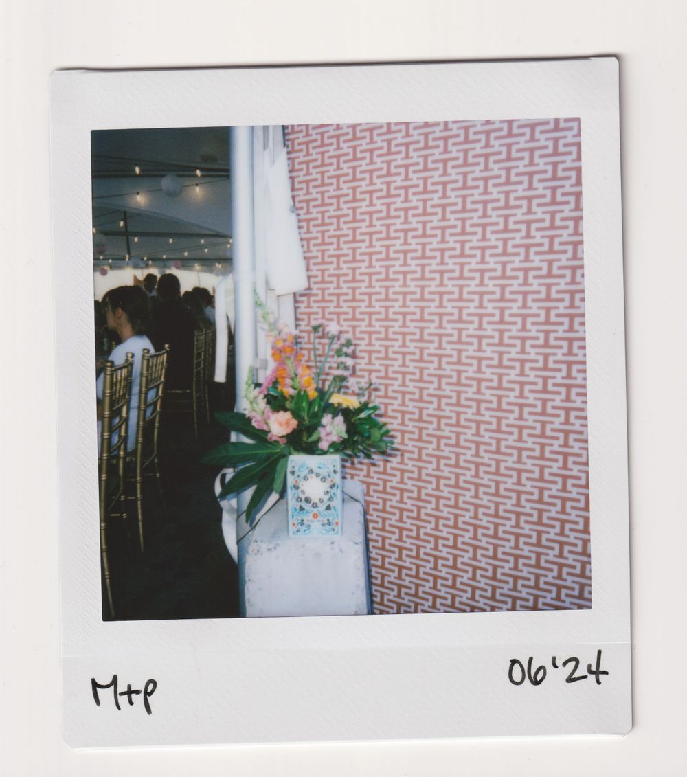 A floral arrangement displayed against a geometric pink and white patterned wallpaper.