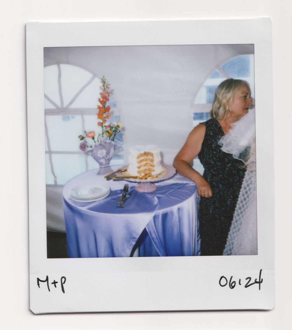 Table set with blue tablecloth and layered cake with floral decorations in bright interior.