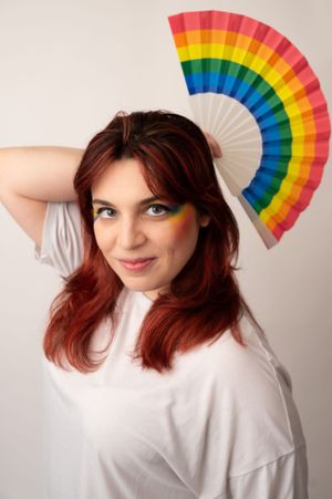 Rainbow paper fan poses against white backdrop in artistic photo series.