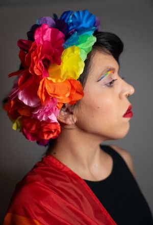 Artistic portrait with vibrant rainbow flower hair accessory and red attire.