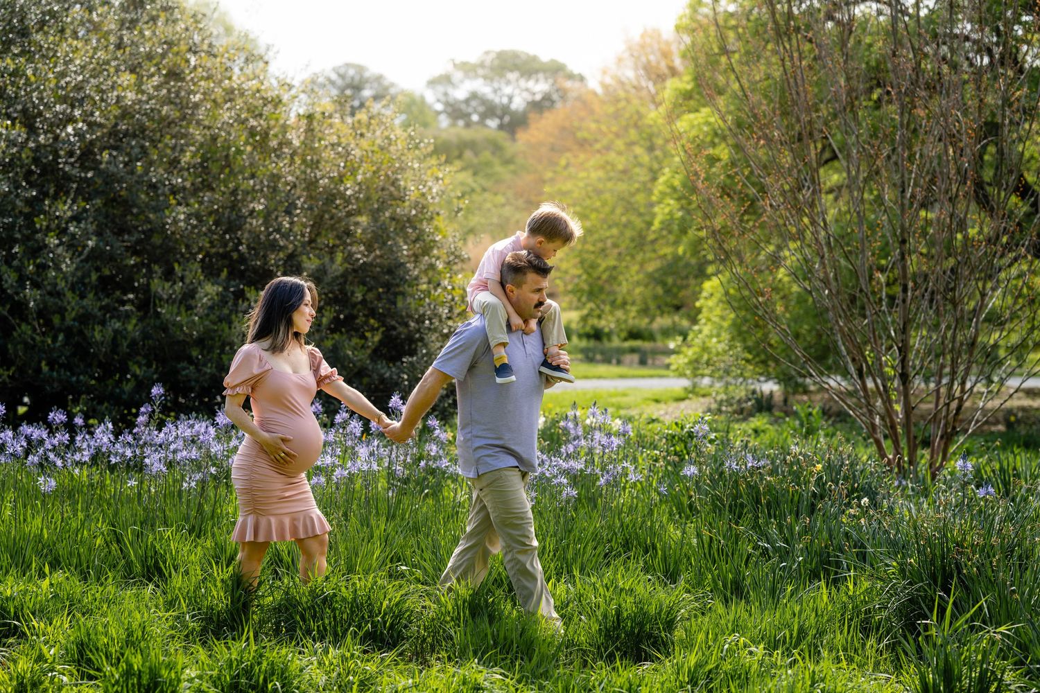 Family walking together through a spring meadow filled with blooming wildflowers on a sunny afternoon.