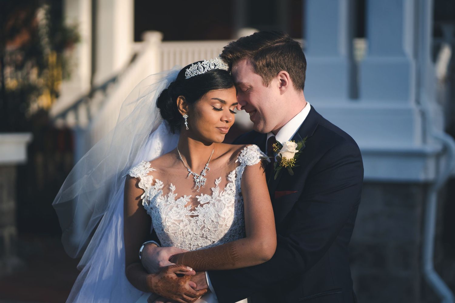 A couple shares an intimate moment together on their wedding day in front of a building during sunset.