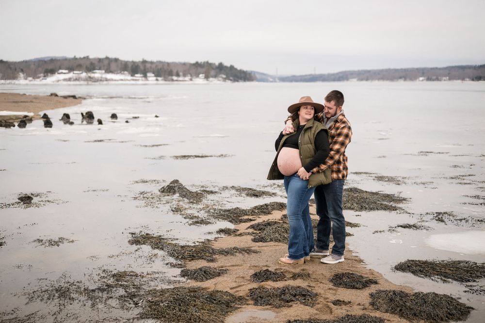 People explore a rocky beach coastline on an overcast winter day at low tide.