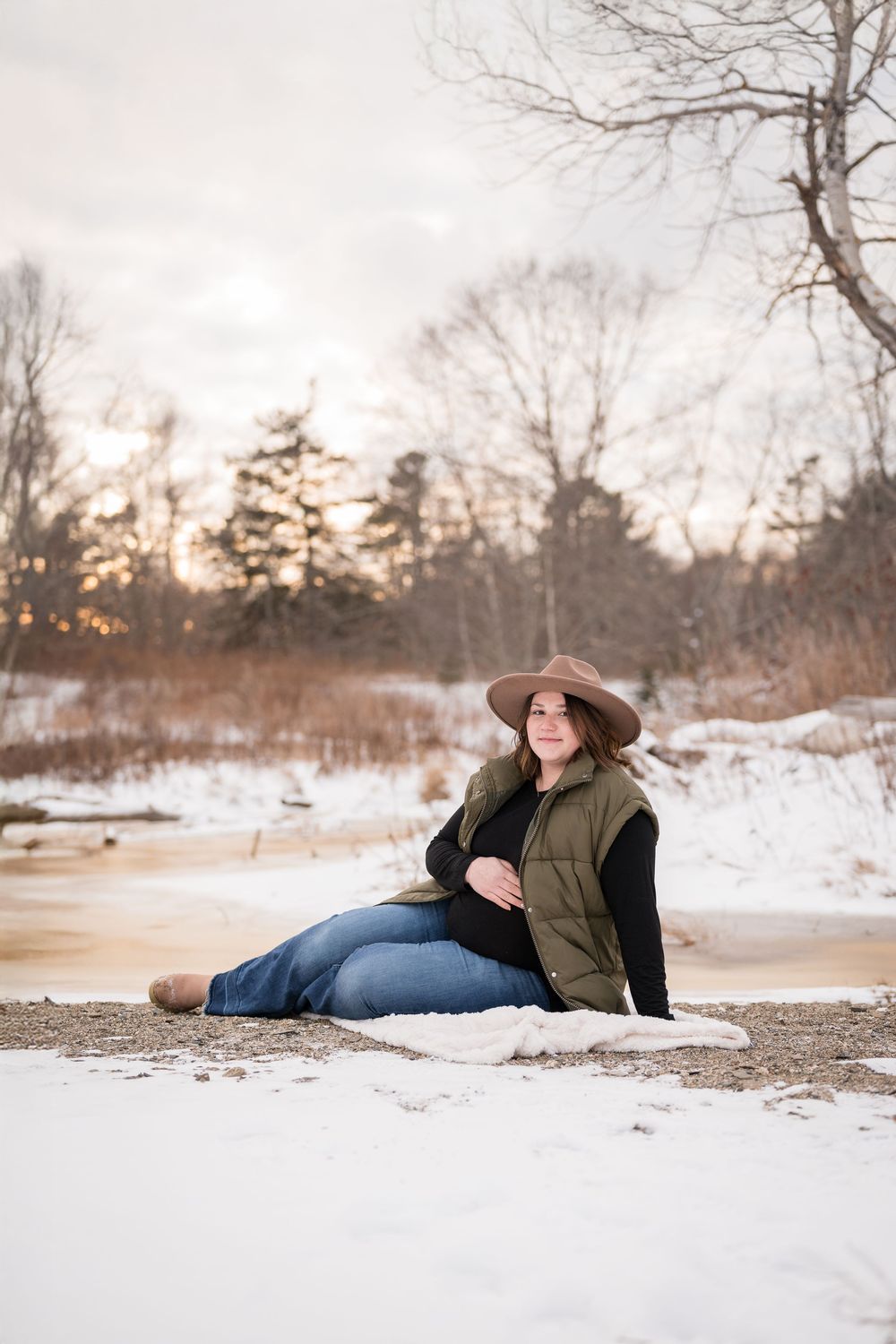 A romantic winter photoshoot on a snowy beach at sunset with soft golden light.