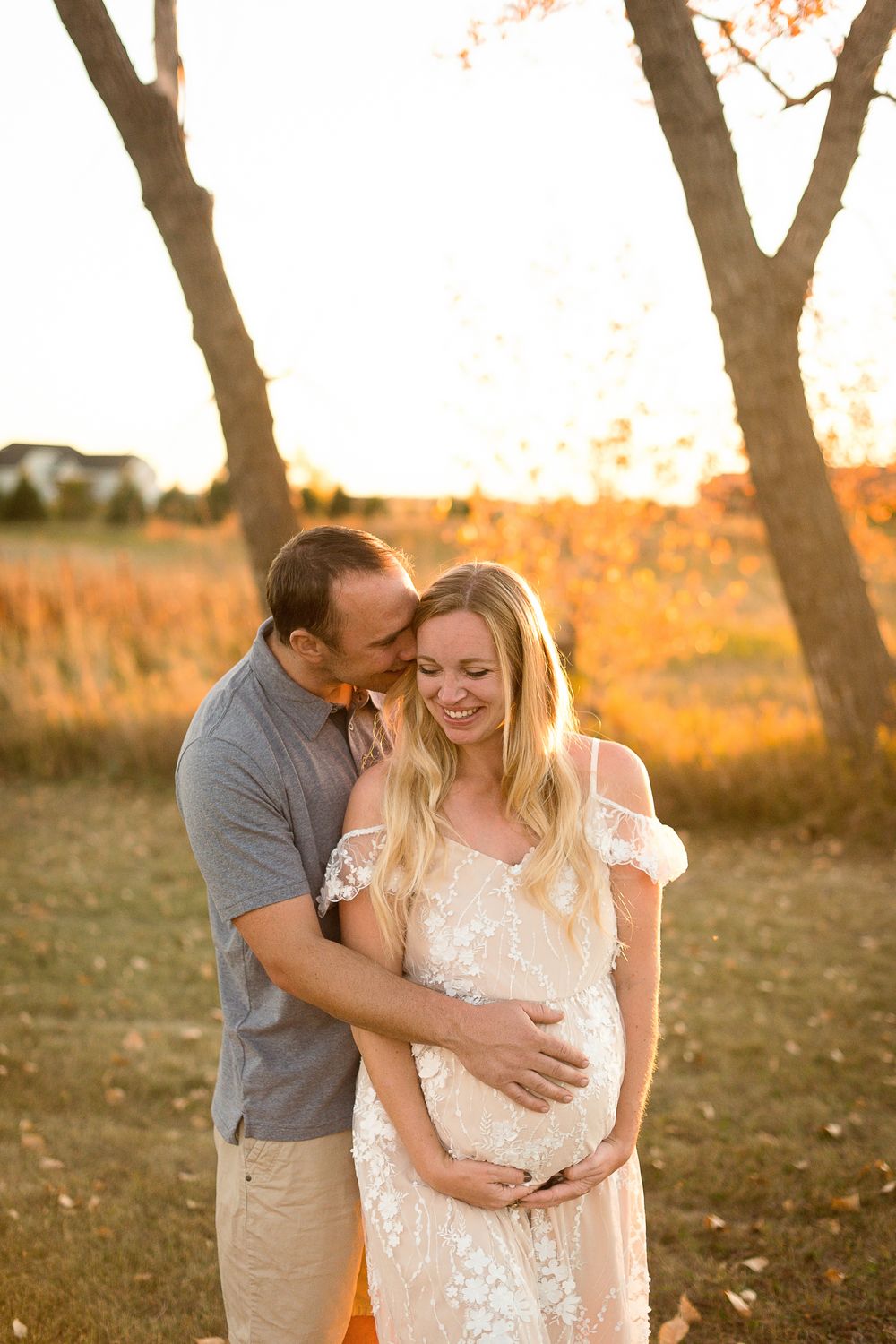 Couple sharing intimate moment during sunset maternity photoshoot.