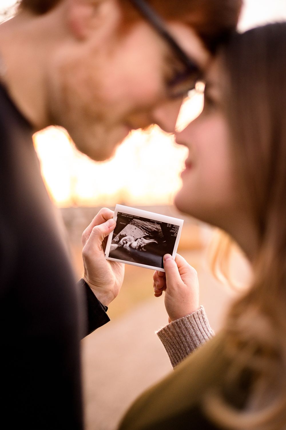Close-up of hands holding black and white ultrasound photos.
