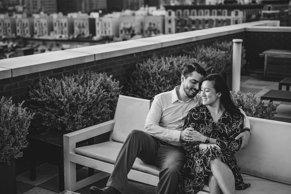 Couple sharing intimate moment on rooftop terrace with city buildings in background.