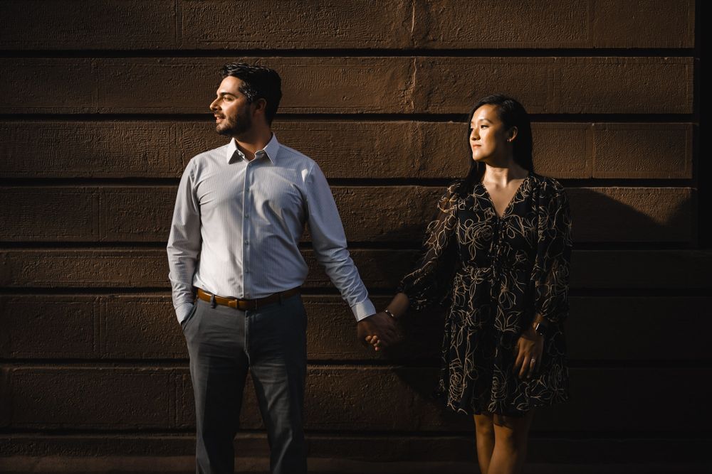 An intimate portrait session against a dark wooden wall with dramatic lighting.