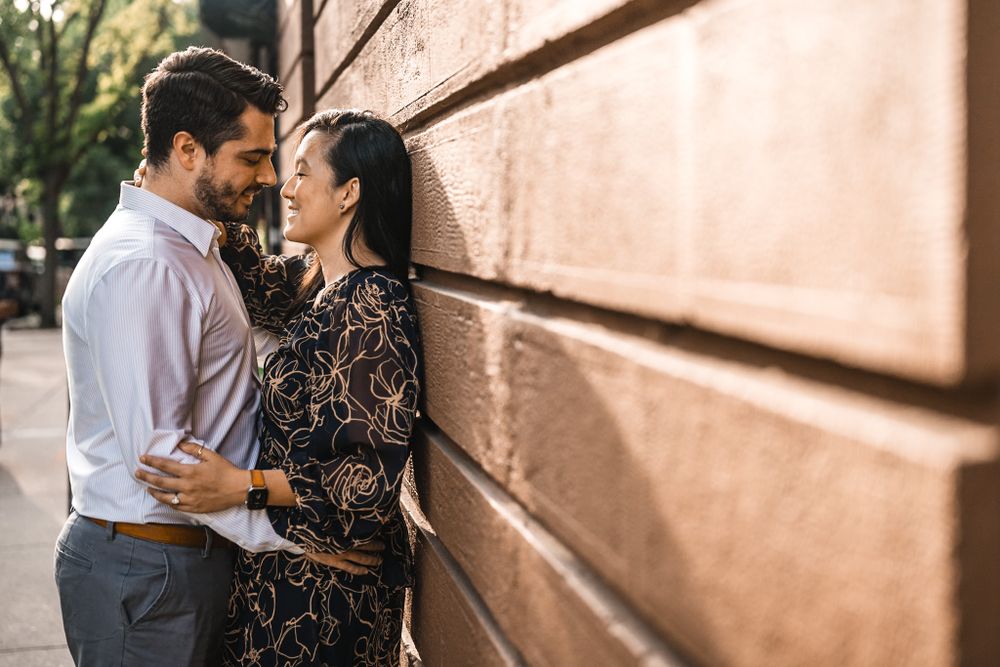 A romantic couple's photoshoot against a sunlit peach-colored wall.