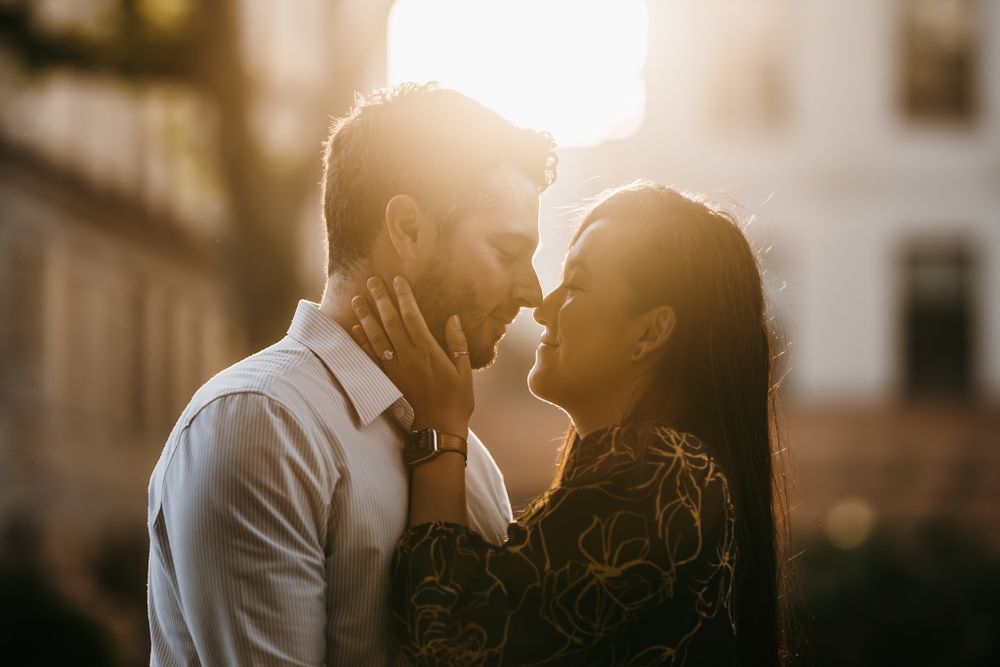 Silhouetted couple embracing against golden sunset light in urban setting.