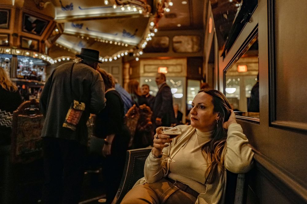Inside a cozy pub with string lights and patrons enjoying drinks at the bar.
