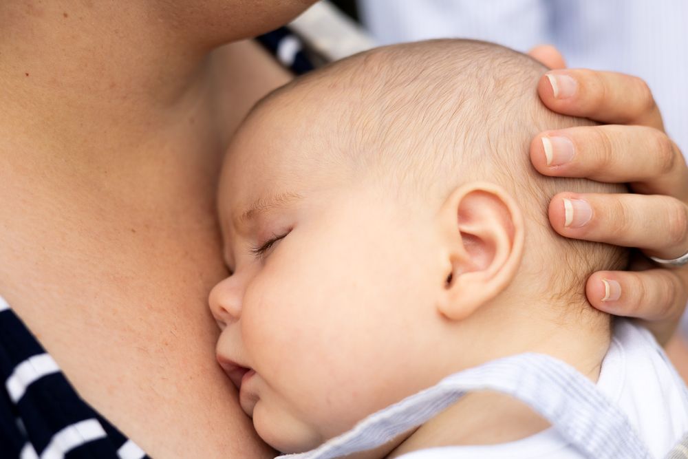 Newborn cuddled in sling - close up