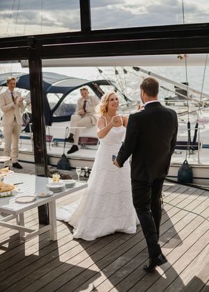 Bride and groom sharing a joyful moment dancing on a sunlit yacht deck at their wedding reception.