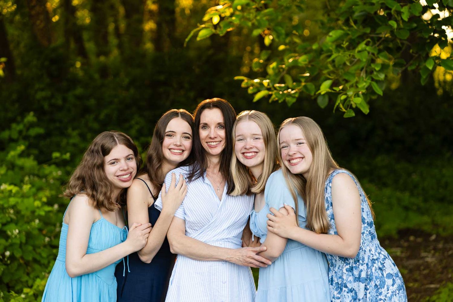 Mother and her daughters pose for portrait in the forest.