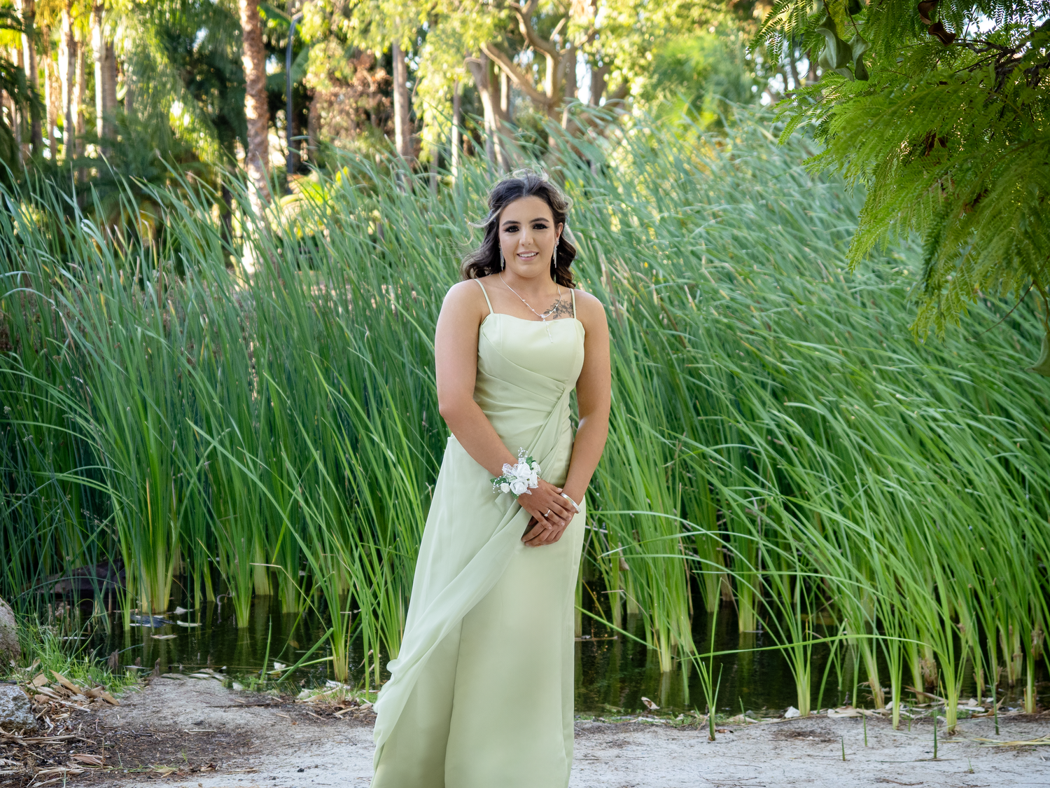 Outdoor school prom photo of teenager wearing a green formal dress with long hair