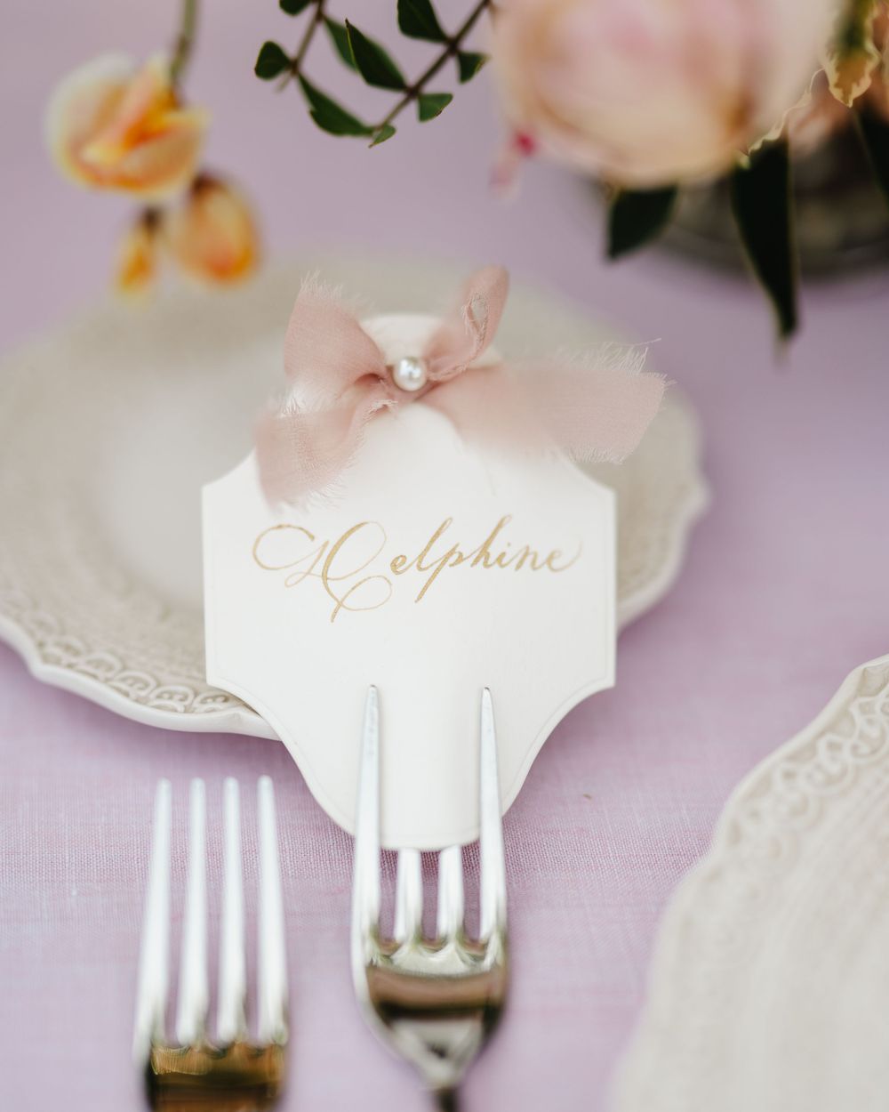 Elegant place card with pink bow decoration and delicate lace details.