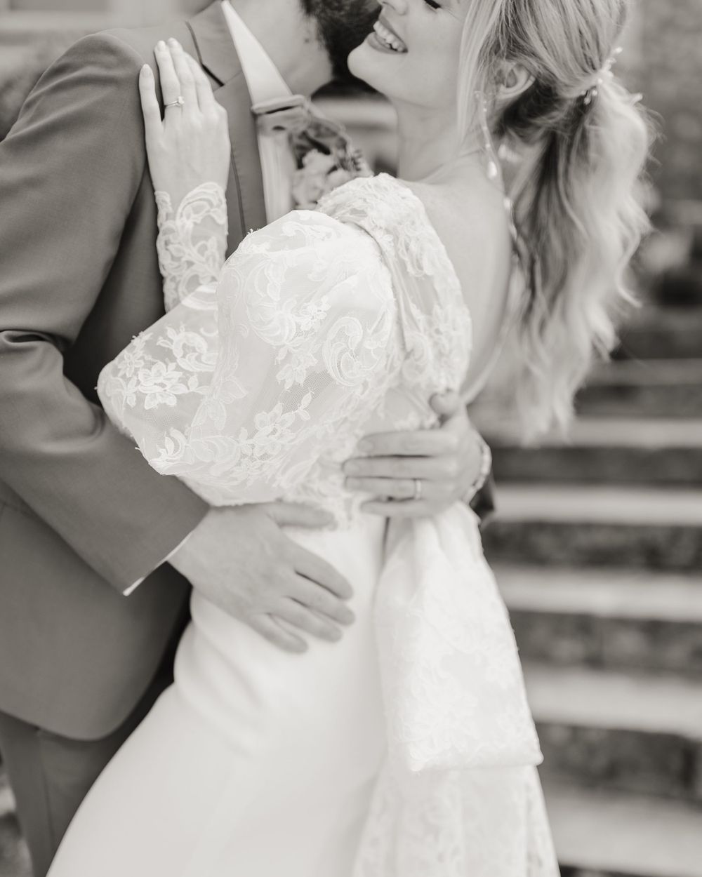 Black and white intimate wedding photo capturing romantic embrace on stone steps.
