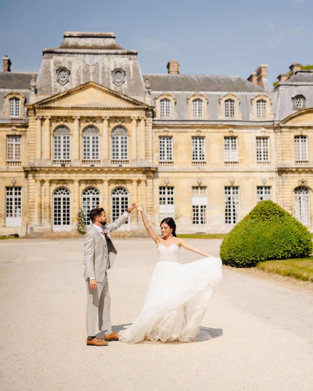 A romantic wedding moment outside a grand French chateau with classical architecture.