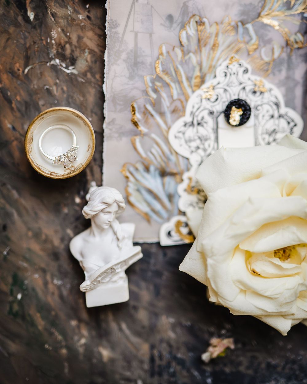 Close-up detail of white roses and wedding stationery against a dark textured background.