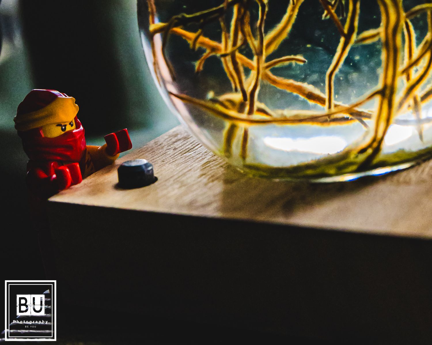 A small red Lego figure sits next to a glass jar filled with glowing yellow fairy lights.