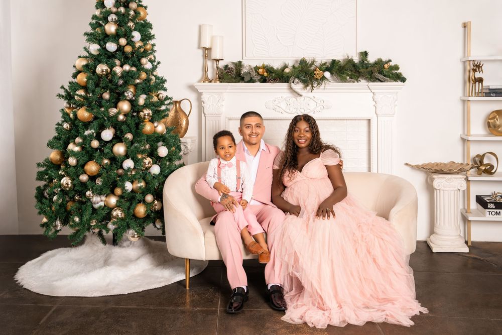 Elegant Christmas photoshoot in white room with decorated tree and fireplace mantel.