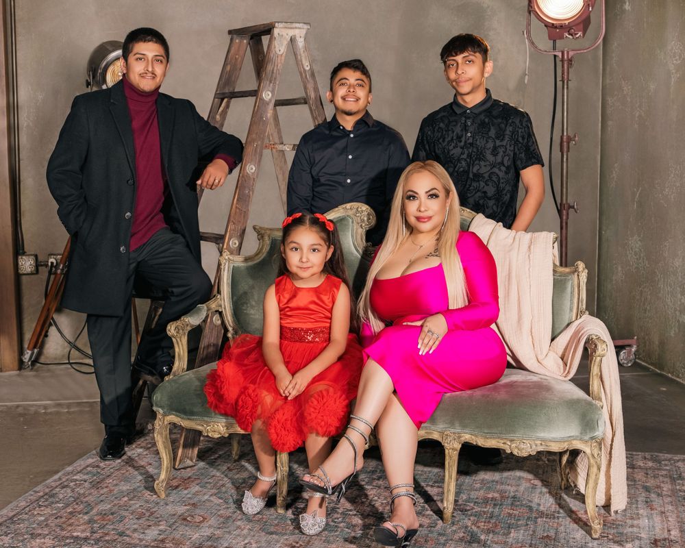 A family poses on antique furniture against an industrial backdrop with a stepladder and studio light.