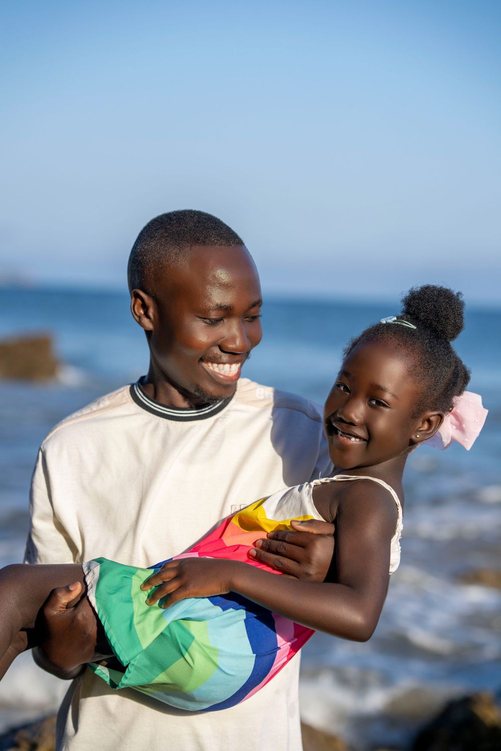 Joyful moment shared between parent and child playing on rocky beach.