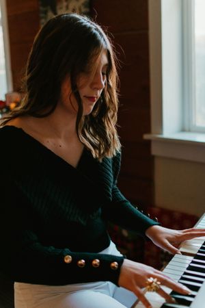 Person playing piano keys in moody indoor lighting.