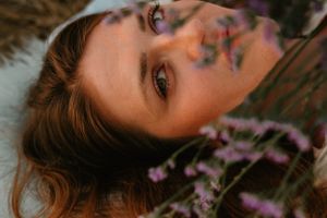 Portrait with purple flowers and warm sunset lighting creates dreamy atmosphere.