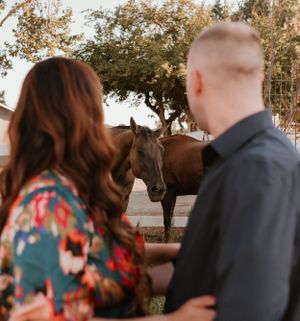 Couple in casual wear standing near white fence during golden hour.