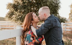 Intimate moment between couple against white fence during sunset photography session.