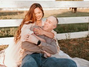 Candid moments captured between couple during sunset photo session by white fence.