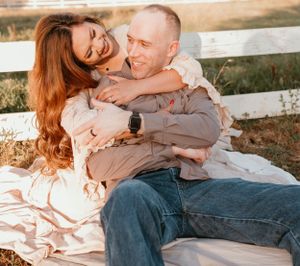 A couple shares an intimate moment while sitting together in warm sunset lighting.