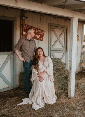 A couple shares intimate moments in a rustic barn setting with hay-covered floors.