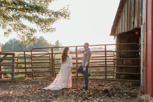 A countryside barn photoshoot with white fencing and natural sunset lighting.