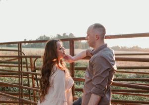 A couple dances together against a rustic fence backdrop during golden hour.