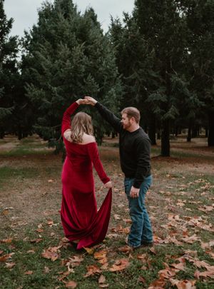 A romantic moment captured in a wooded area with scattered autumn leaves on the ground.