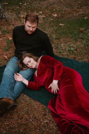 Two people share a quiet moment on a blanket in an autumn forest scene.