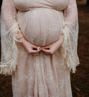 Close-up shots of a flowing white lace maternity dress in a forest setting.