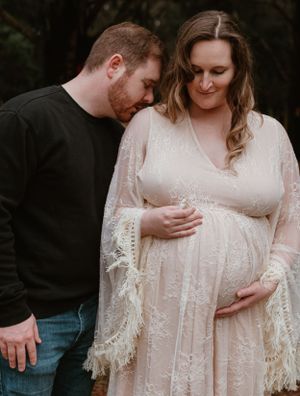 Intimate maternity photography showing couple embracing in autumn forest setting.