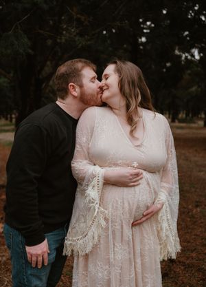 Tender moment captured during outdoor maternity session with couple in autumn setting.