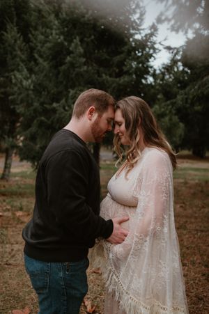 Fall maternity session featuring couple sharing tender moments in wooded setting.