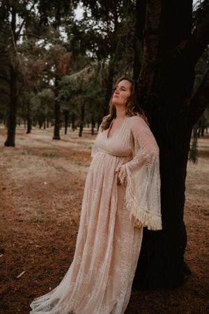 Whimsical forest photoshoot featuring a flowing blush-colored dress with delicate lace details.